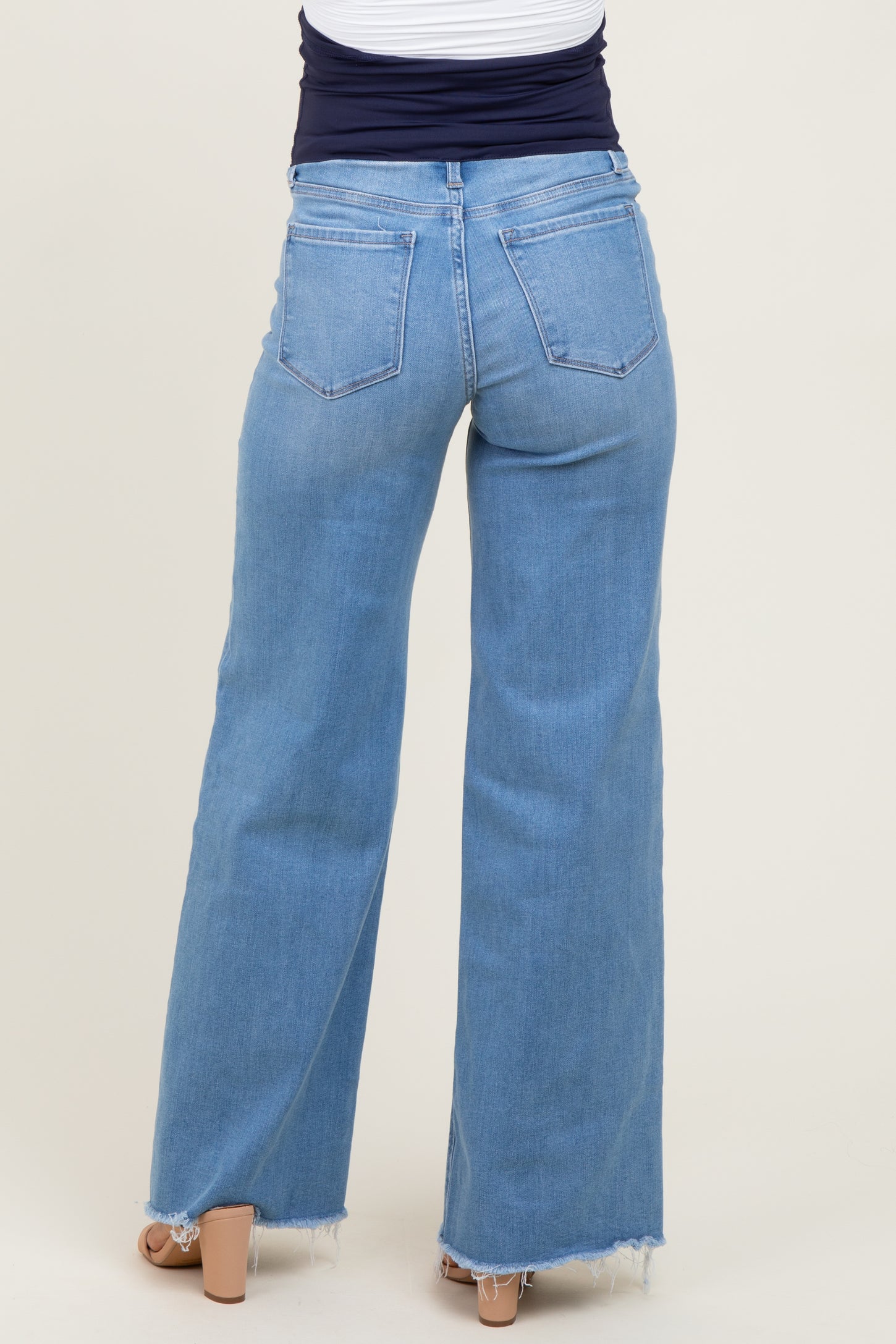 maternity wear light wash wide leg jeans with frayed hem, view of the back, model wearing them with a navy top