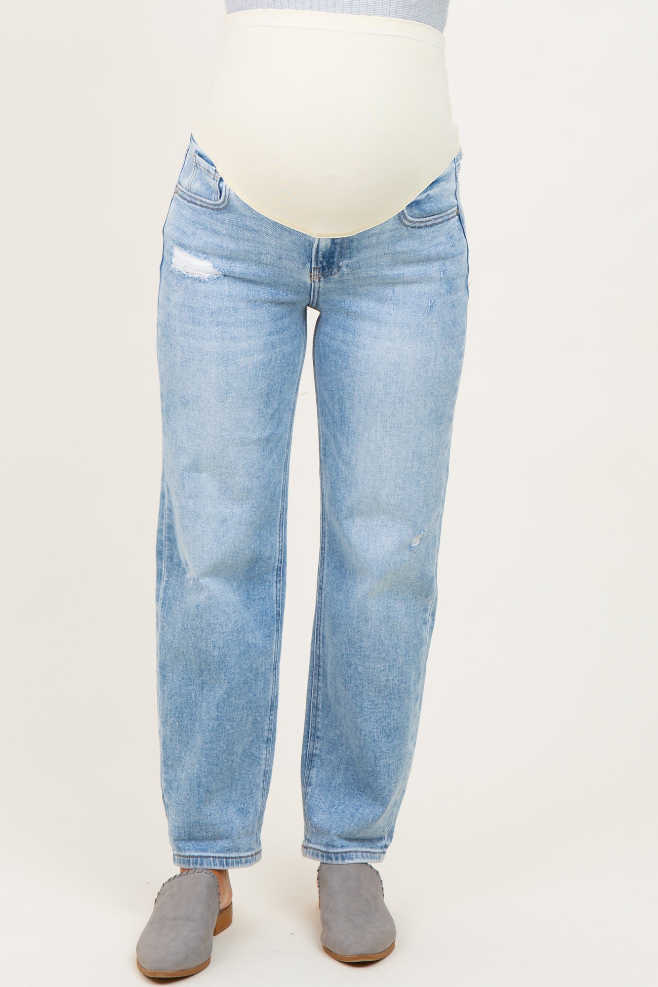 woman wearing light blue distressed maternity jeans with a supportive belly band and gray suede clogs