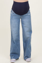 woman wearing light blue maternity jeans with a dark blue over-the-bump waistband and white sneakers
