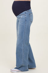woman wearing light blue distressed maternity jeans with a navy top and showing her baby bump