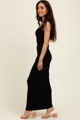woman wearing a black sleeveless maxi dress and nude block-heeled sandals, posed sideways with a smile
