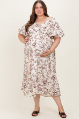 woman wearing a cream floral print maternity plus maxi dress and holding her baby bump