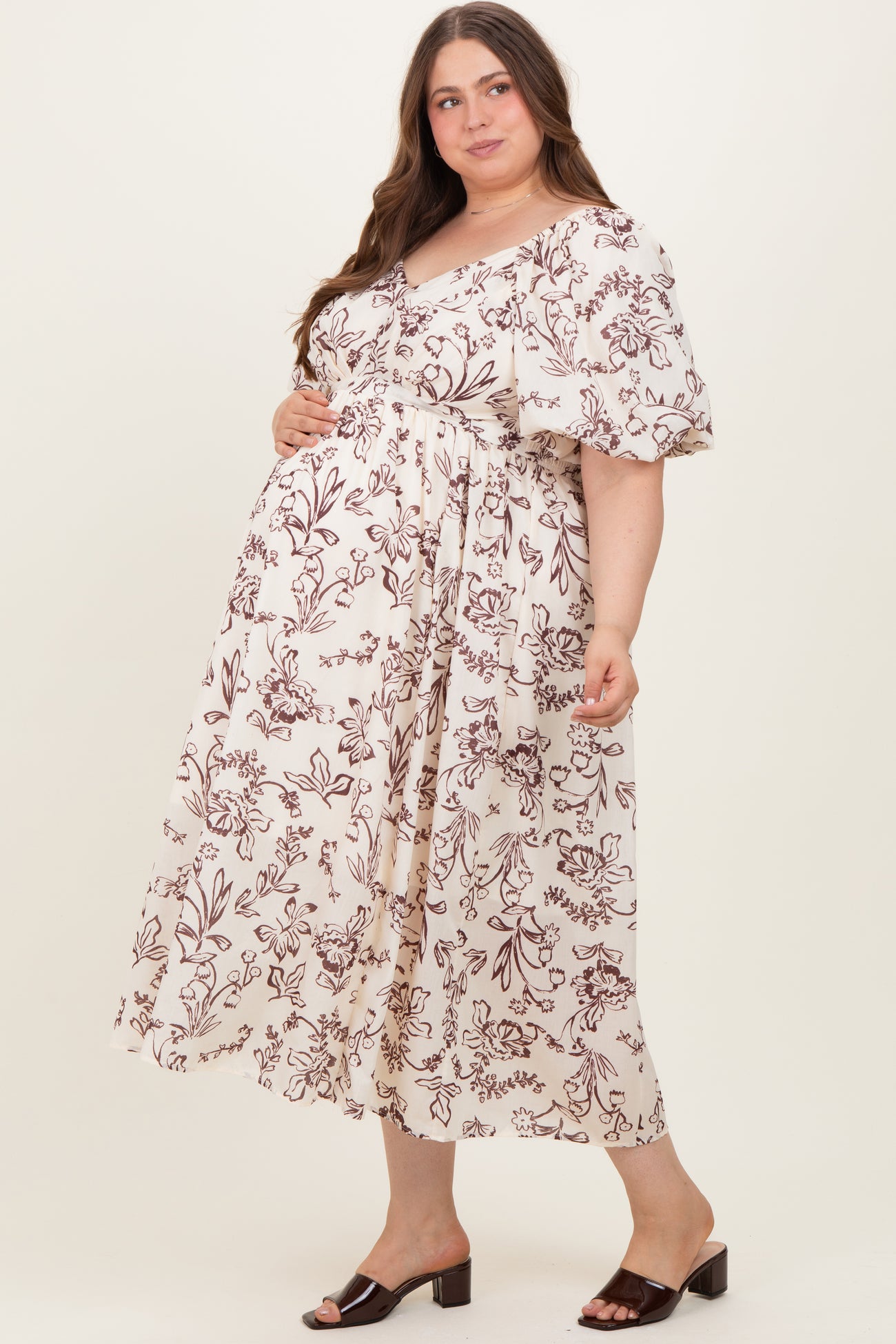 woman wearing a cream floral maternity maxi dress with short ruffled sleeves and a baby bump visible