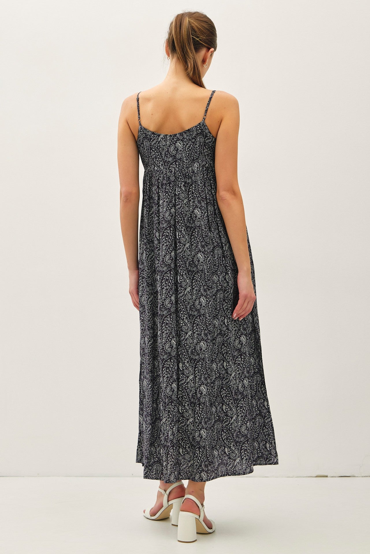 woman wearing a back view of a black and white patterned maxi dress with thin straps