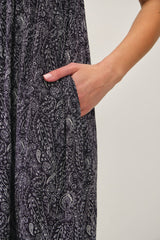 woman wearing a dark purple paisley patterned dress with pockets