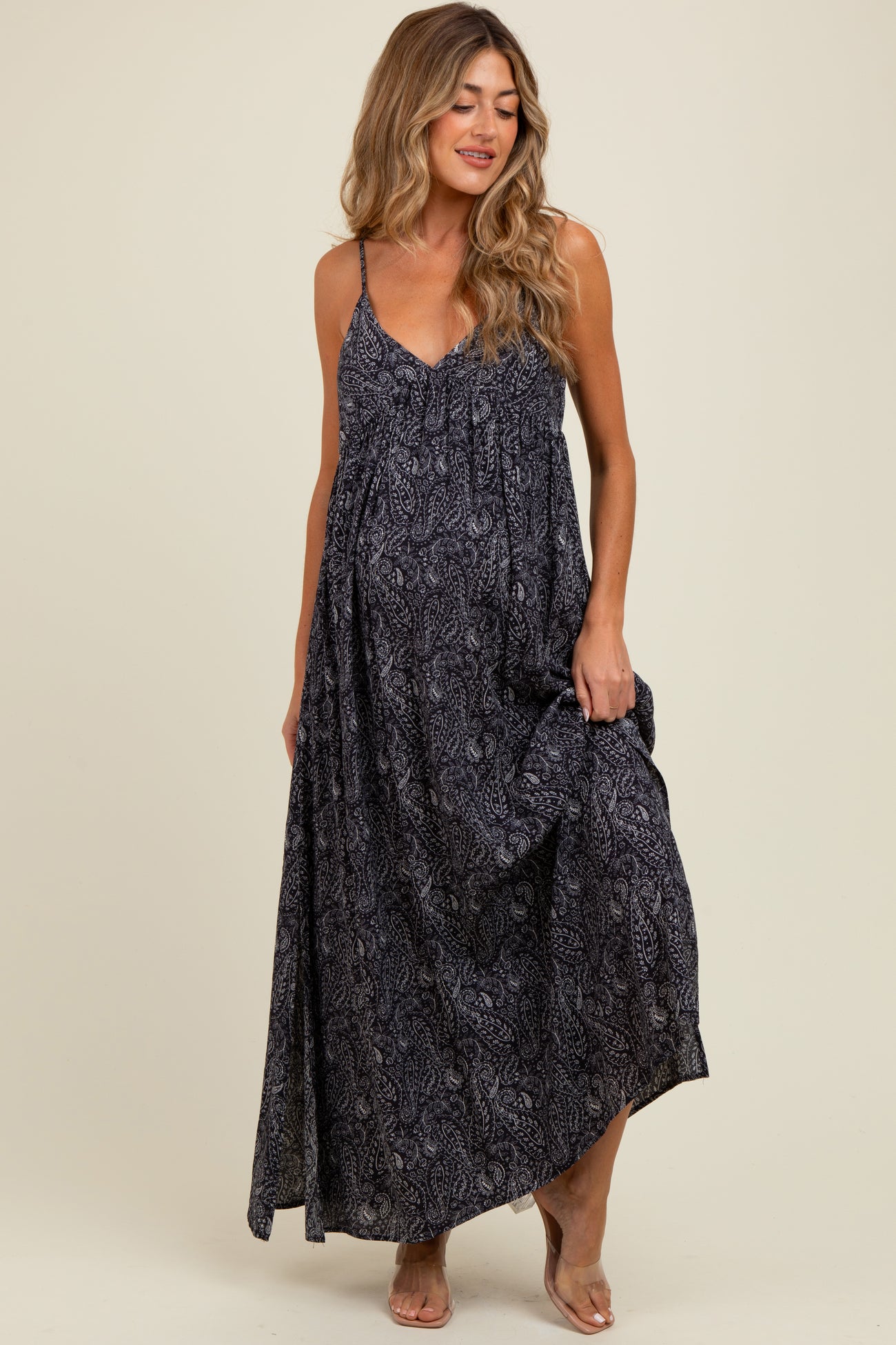 woman wearing a black and white patterned maternity maxi dress with adjustable straps and a flowing silhouette, showing her baby bump