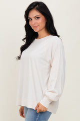 woman wearing a light beige long sleeve top with relaxed fit and balloon sleeves paired with blue jeans