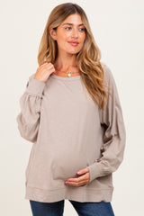 woman wearing a taupe long sleeve maternity top and holding her baby bump in a casual pose