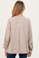 woman wearing a beige maternity top with a relaxed fit and stylish back detail