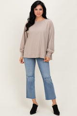 woman wearing a beige long sleeve loose top with balloon sleeves paired with light blue cropped jeans and black mules