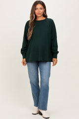 woman wearing a dark green maternity sweatshirt with raglan sleeves paired with light blue jeans