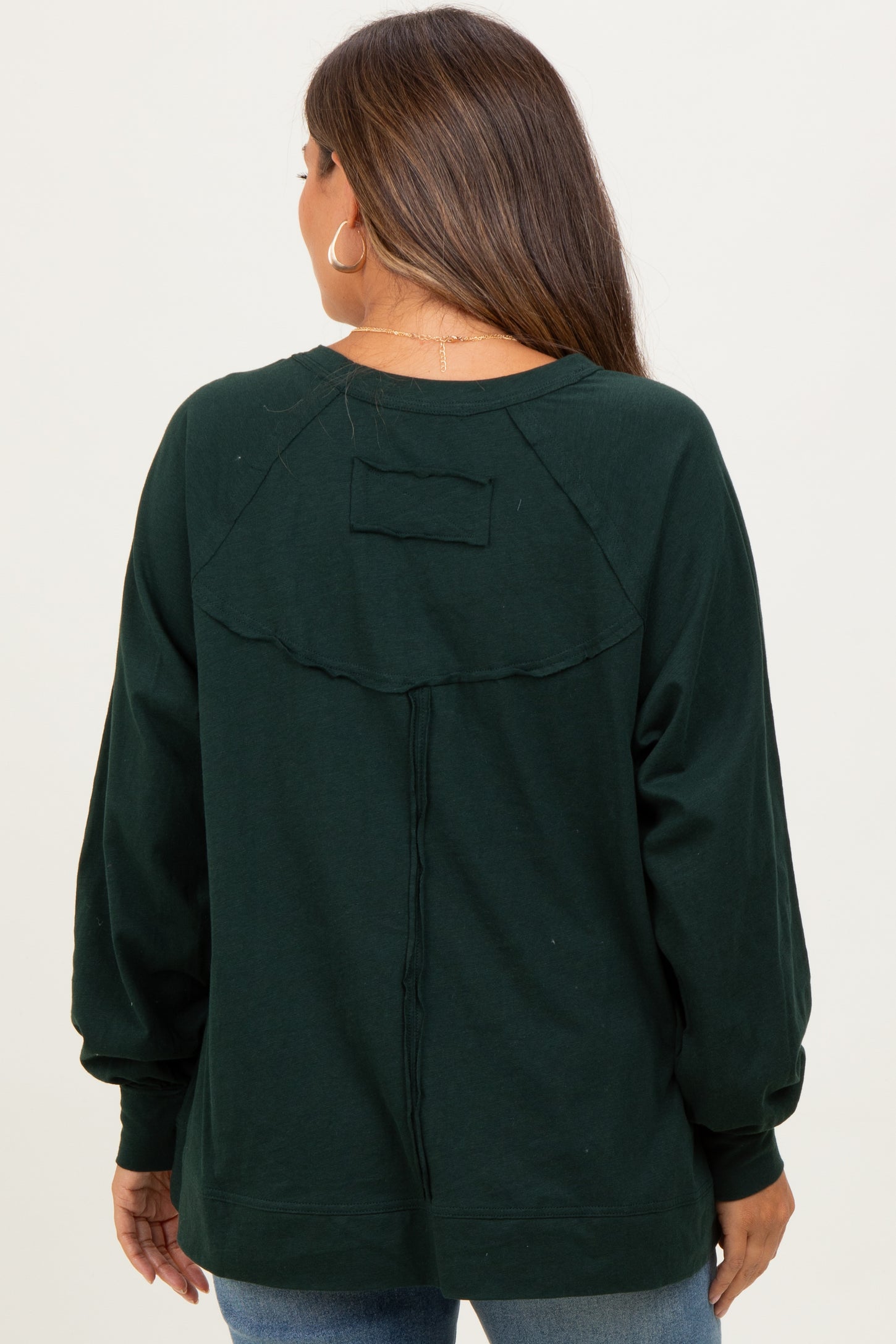 woman wearing a dark green maternity sweatshirt with balloon sleeves and a back seam detail