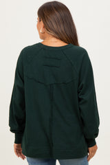 woman wearing a dark green maternity sweatshirt with balloon sleeves and a back seam detail