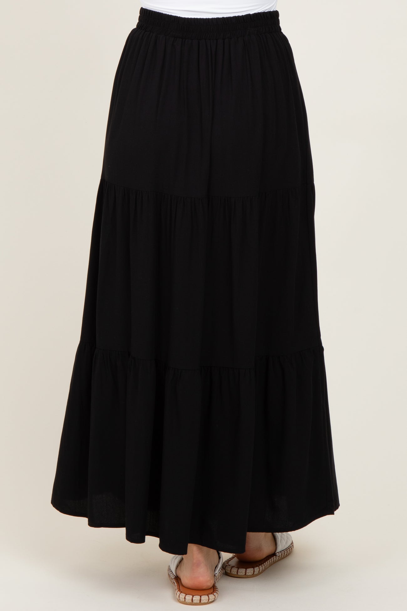 woman wearing a black tiered maxi skirt with an elastic waistband and flowy hemline