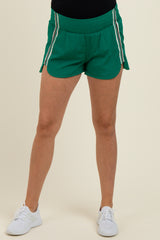woman wearing green maternity athletic shorts with white side stripes and an elastic waistband