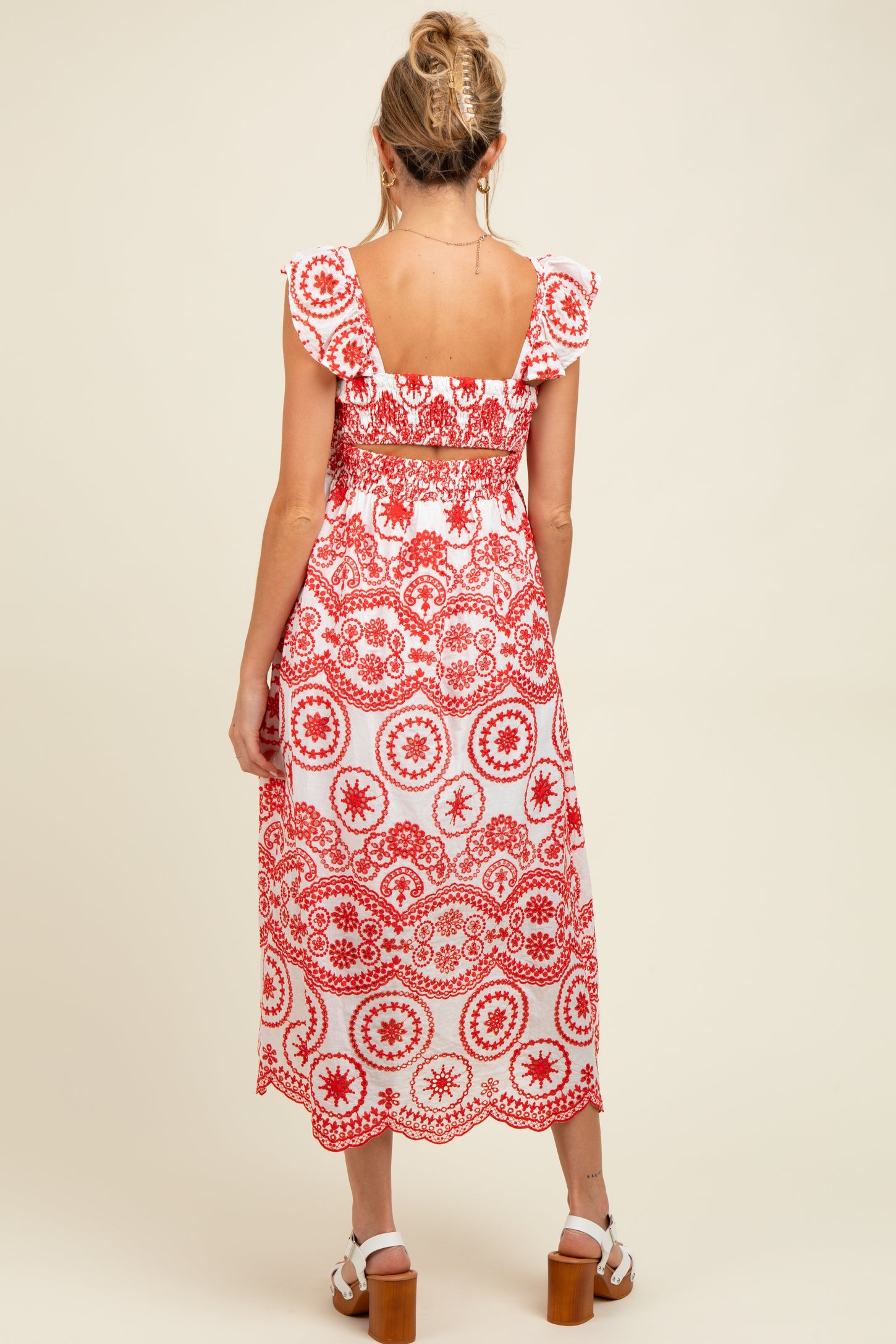 woman wearing a red and white floral print maternity dress with ruffle sleeves and a smocked back