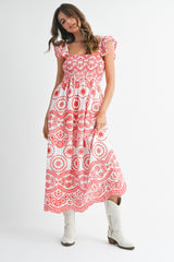 woman wearing a red and white patterned maxi dress with ruffled sleeves and holding the skirt while wearing white boots
