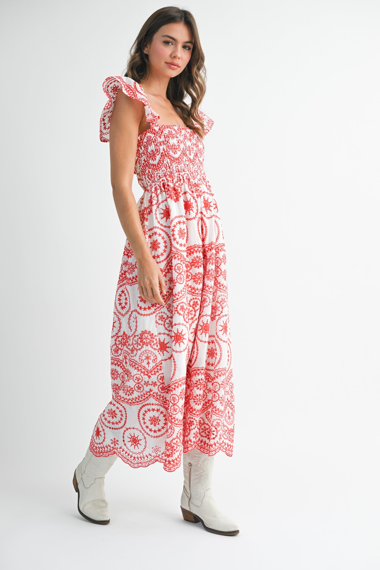 woman wearing a red and white printed maxi dress with ruffle sleeves and standing in a pose with cowboy boots