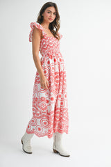 woman wearing a red and white printed maxi dress with ruffle sleeves and standing in a pose with cowboy boots