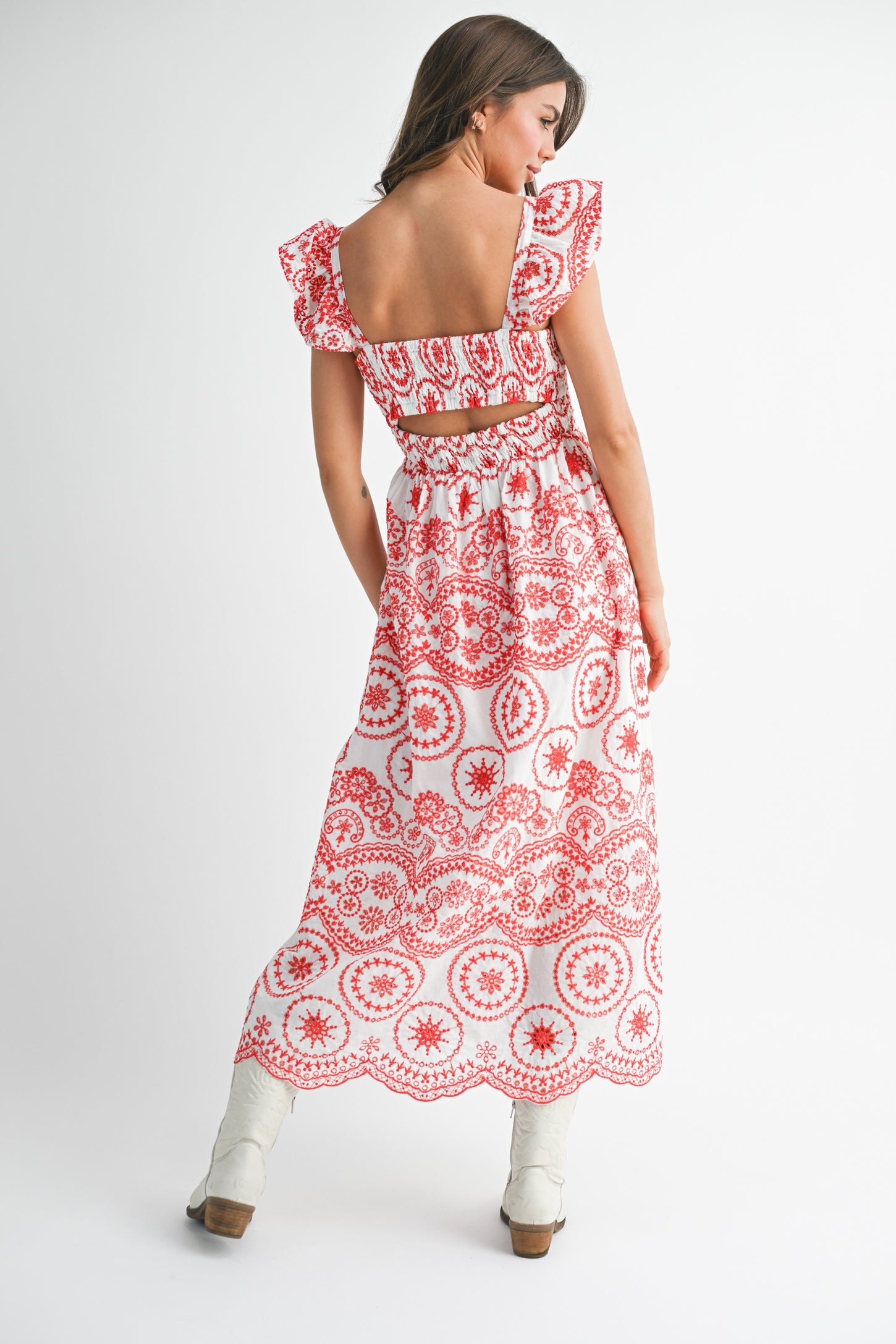 woman wearing a white maxi dress with red floral print and ruffled sleeves, showing the back view