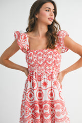 woman wearing a red and white patterned smocked sundress with ruffled sleeves