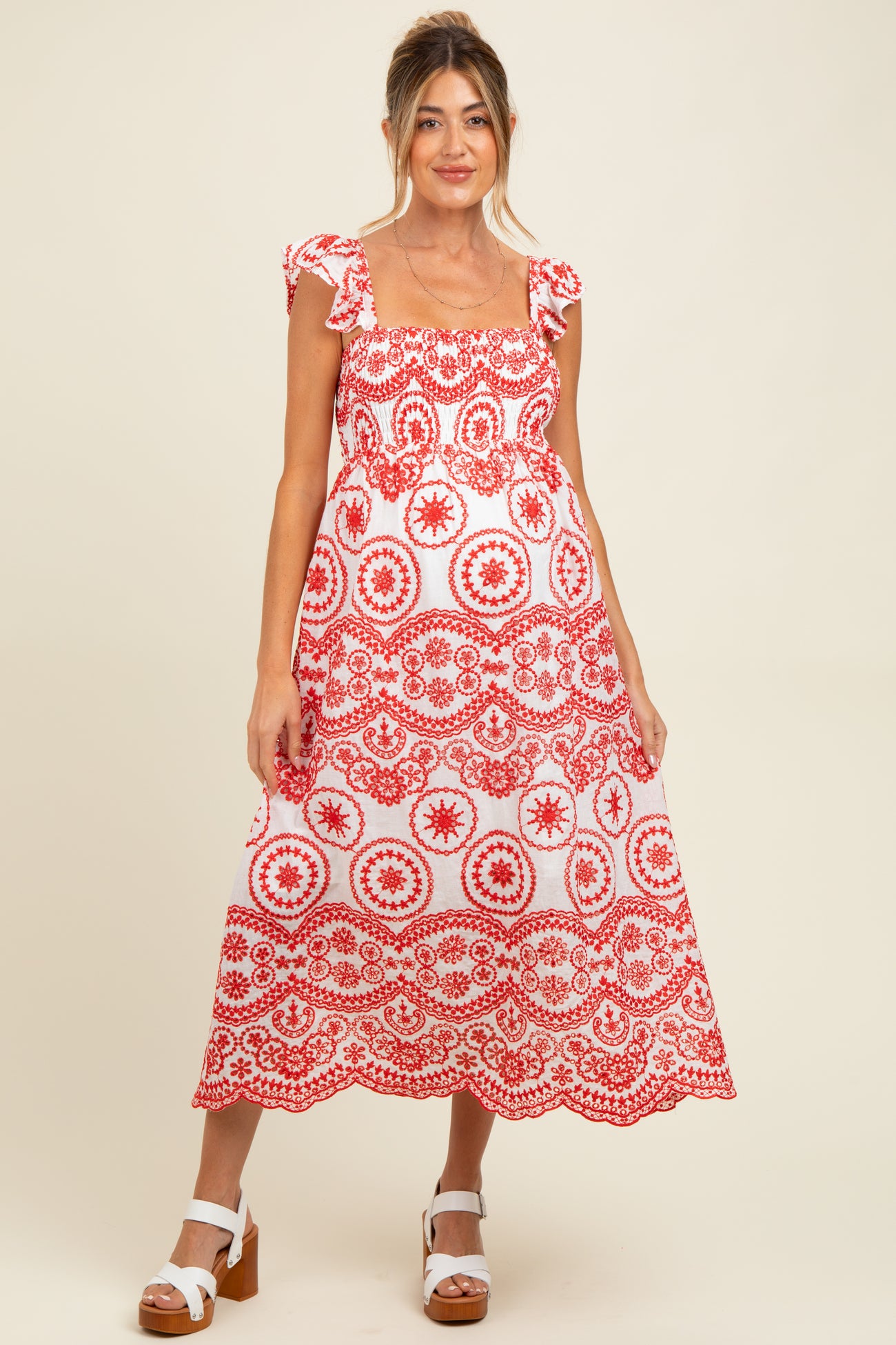 woman wearing a red and white patterned maternity dress with ruffled sleeves and a flowing skirt, baby bump visible