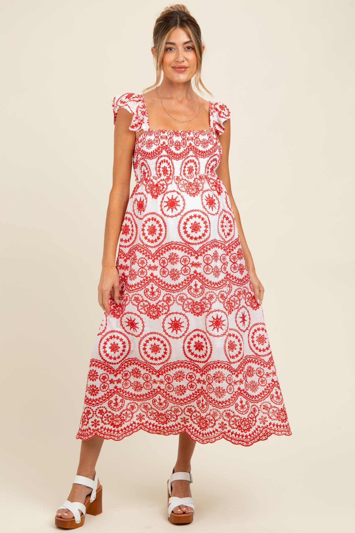 woman wearing a red and white patterned maternity dress with ruffled sleeves and a flowing skirt, baby bump visible