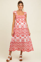 woman wearing a red and white patterned maternity dress with ruffled sleeves and a flowing skirt, baby bump visible