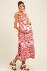 woman wearing a red and white patterned maternity maxi dress with ruffled sleeves and holding her baby bump