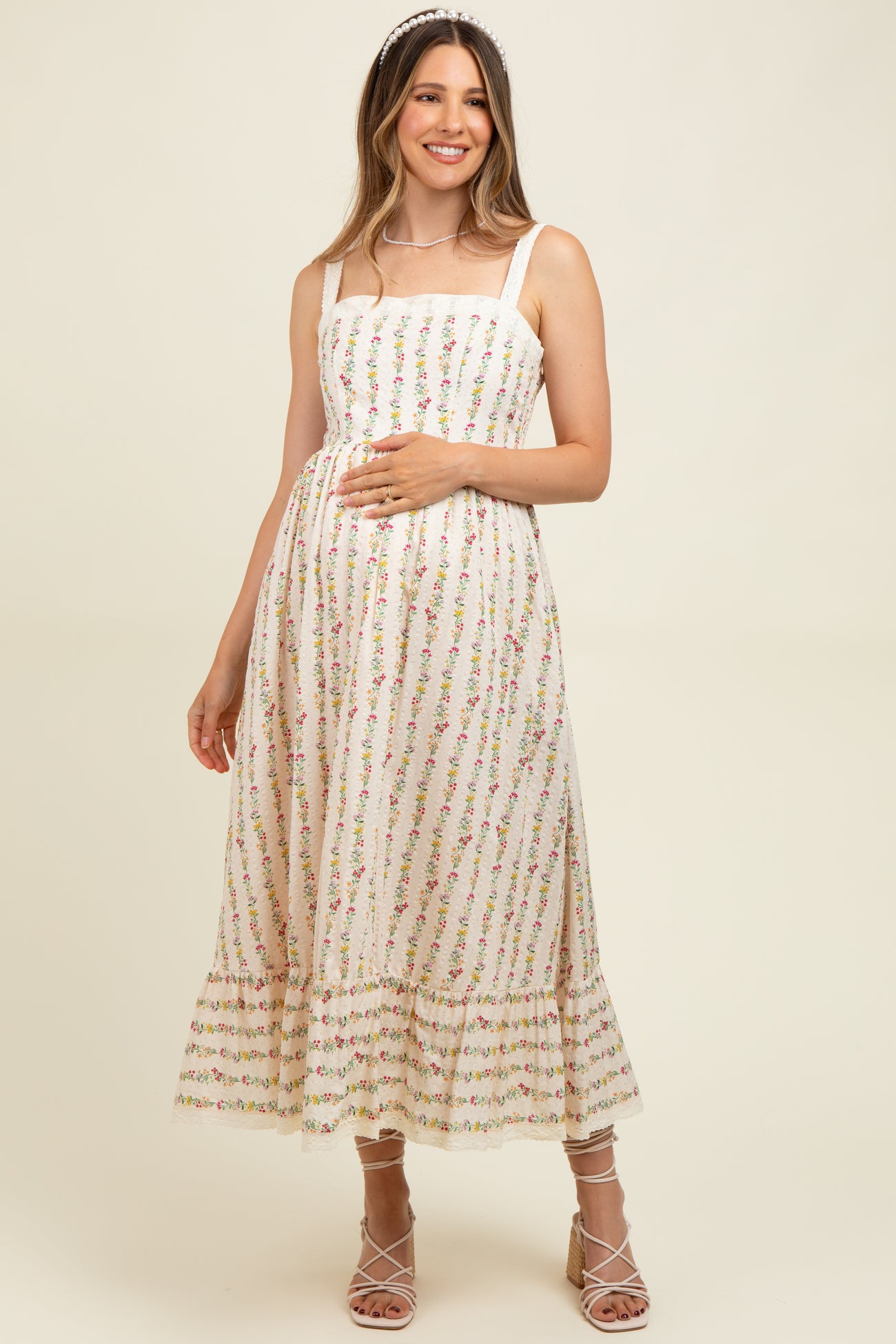 woman wearing a floral print maternity maxi dress with a tiered hem and holding her baby bump