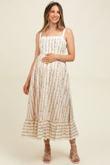 woman wearing a floral print maternity maxi dress with a tiered hem and holding her baby bump