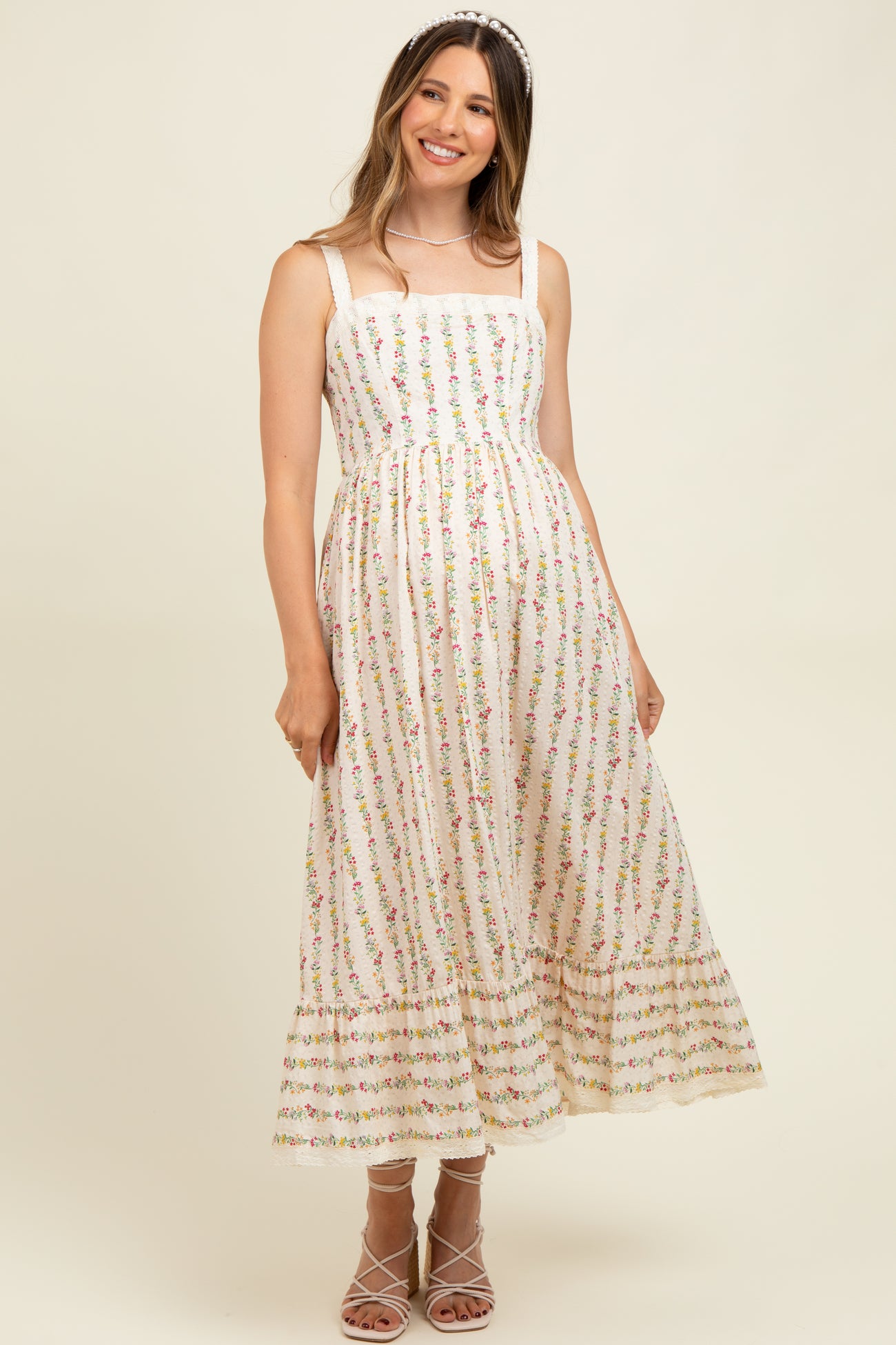 woman wearing a floral print maternity dress with a fitted bodice and flared skirt, showcasing a baby bump