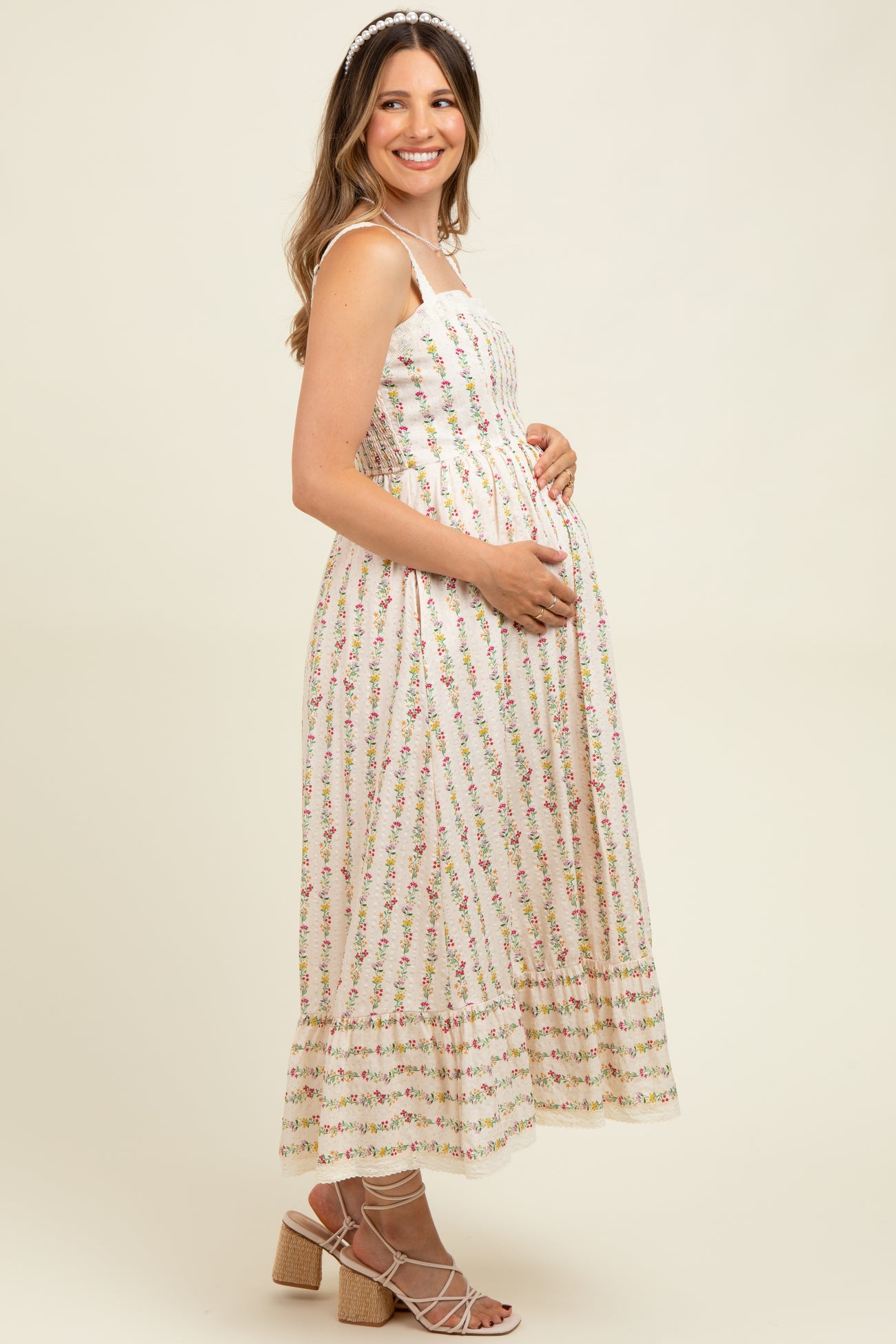 woman wearing a floral print maternity dress with spaghetti straps and a visible baby bump