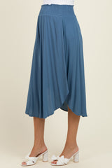 maternity wear blue maxi skirt with a smocked waist and asymmetrical hem, model wearing white heeled sandals