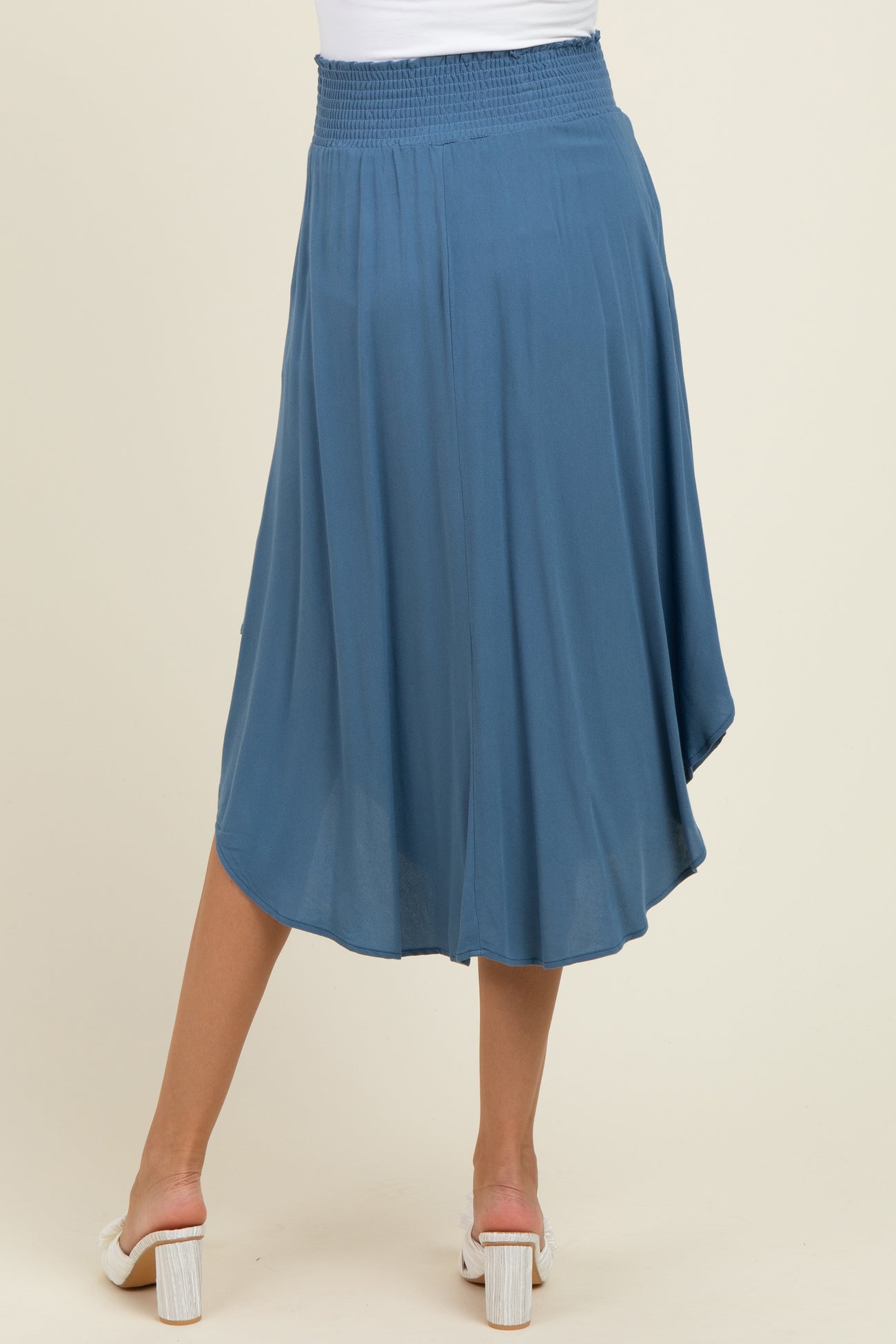 woman wearing a flowy blue maternity skirt with a smocked waist and a slight hi-low hem