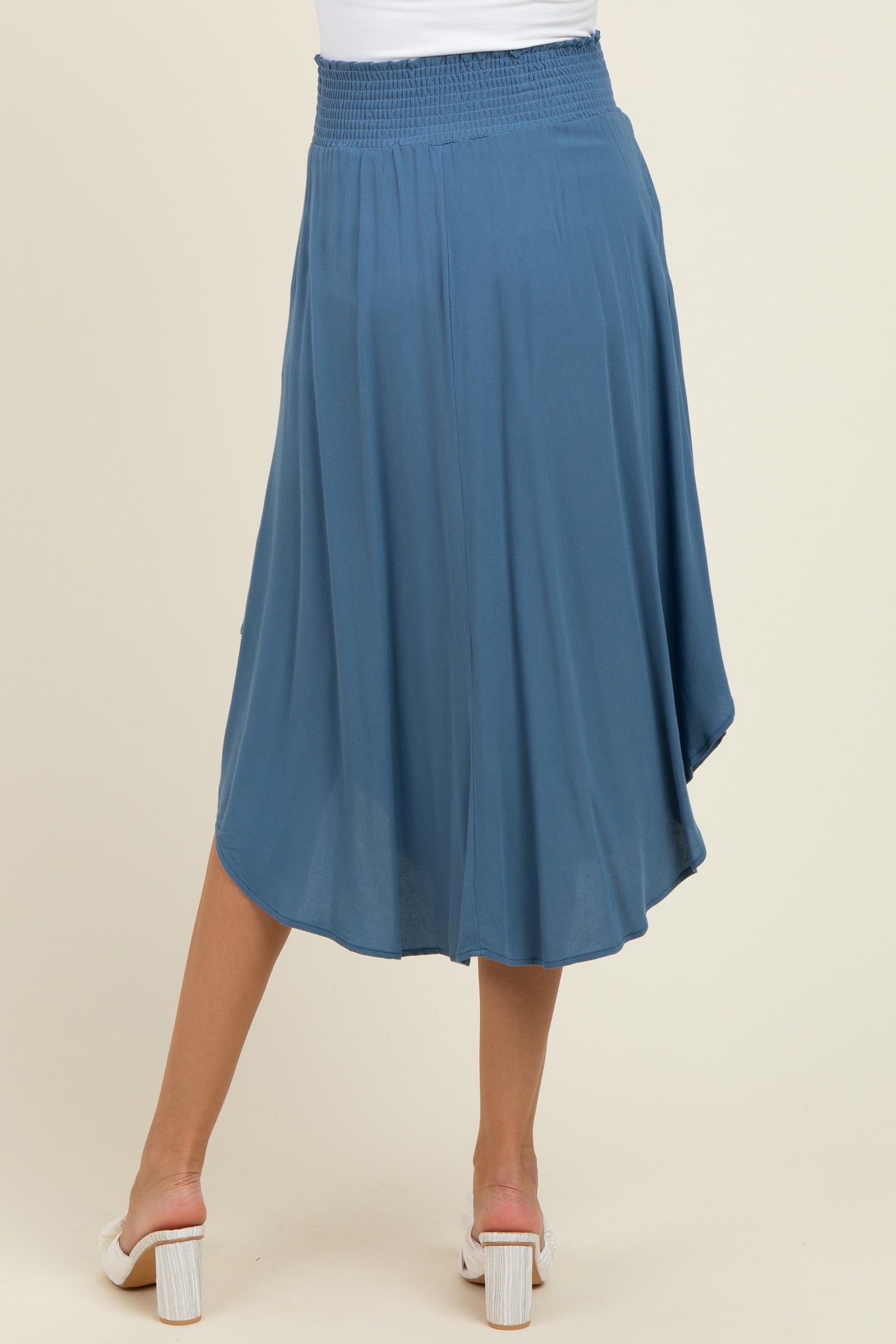 woman wearing a flowy blue maternity skirt with a smocked waist and a slight hi-low hem