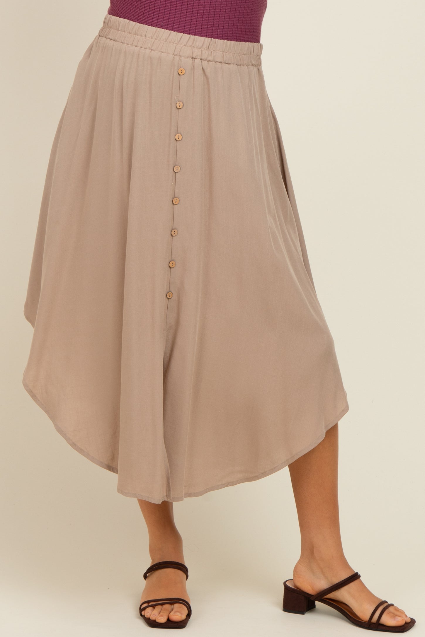 woman wearing a taupe maternity midi skirt with a flowy silhouette and button detailing at the front