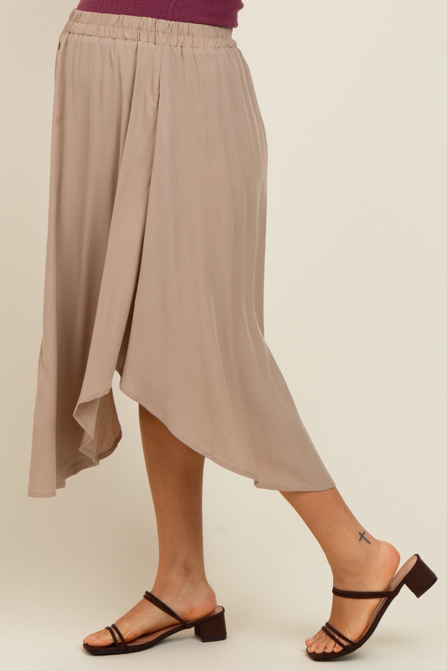 woman wearing a beige maternity skirt with an asymmetrical hem and a comfortable elastic waistband