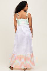 woman wearing a striped maternity maxi dress with a soft green smocked bodice and a flowy striped skirt