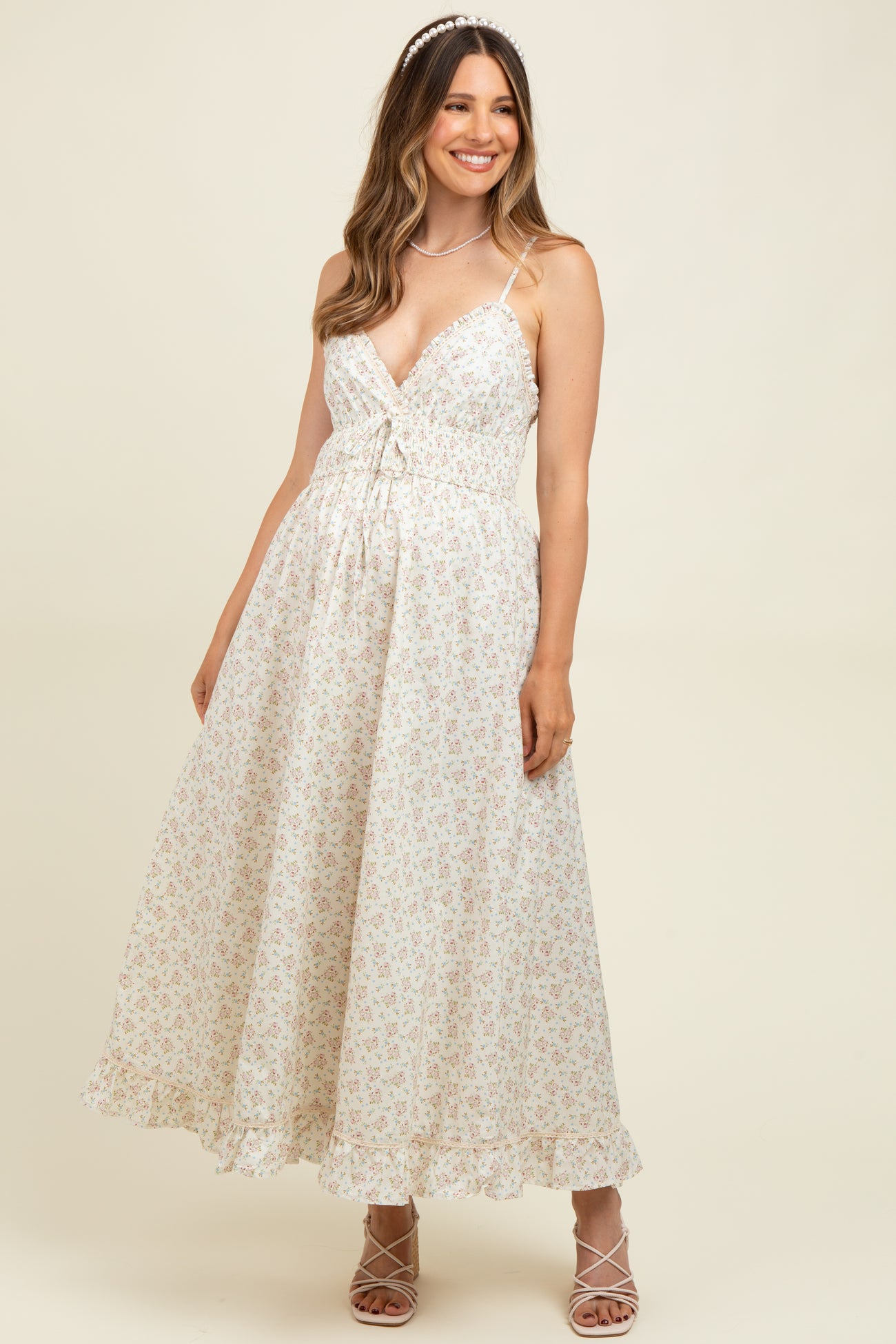 woman wearing a floral print maternity maxi dress with a fitted bodice and flared skirt, smiling and posing.