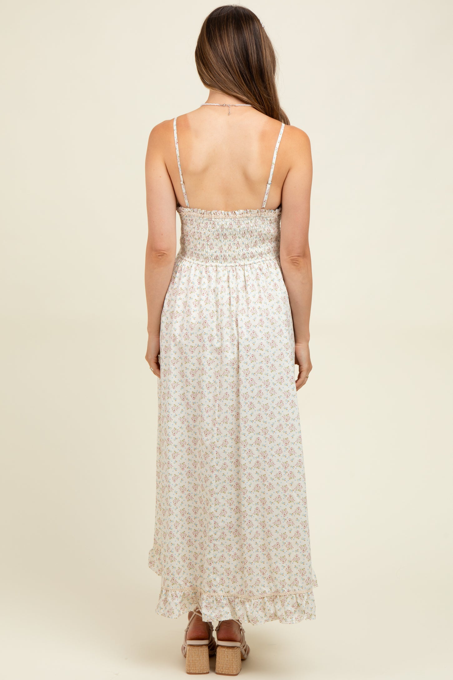 woman wearing a light floral print maternity maxi dress with a smocked back and adjustable straps