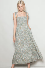 woman wearing a light green floral maxi dress with adjustable tie straps and a smocked bodice