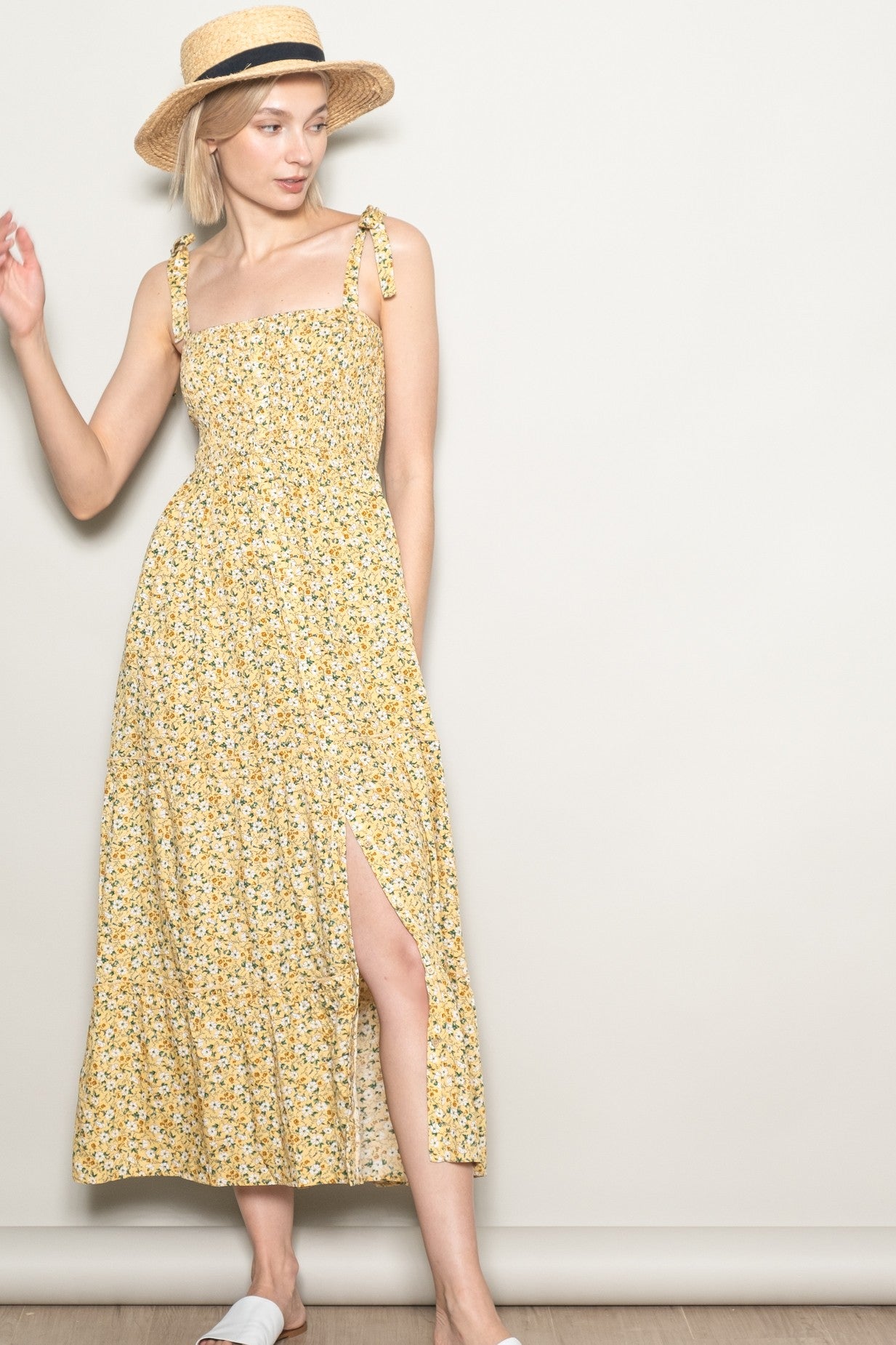 woman wearing a yellow floral maxi dress with tie straps and a side slit