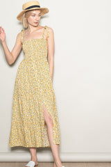 woman wearing a yellow floral maxi dress with tie straps and a side slit