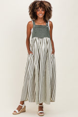 woman wearing a green and white striped maternity dress with a denim top and pockets, showcasing her baby bump