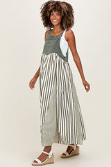 woman wearing a green and white striped maternity maxi dress with overalls, showcasing a visible baby bump
