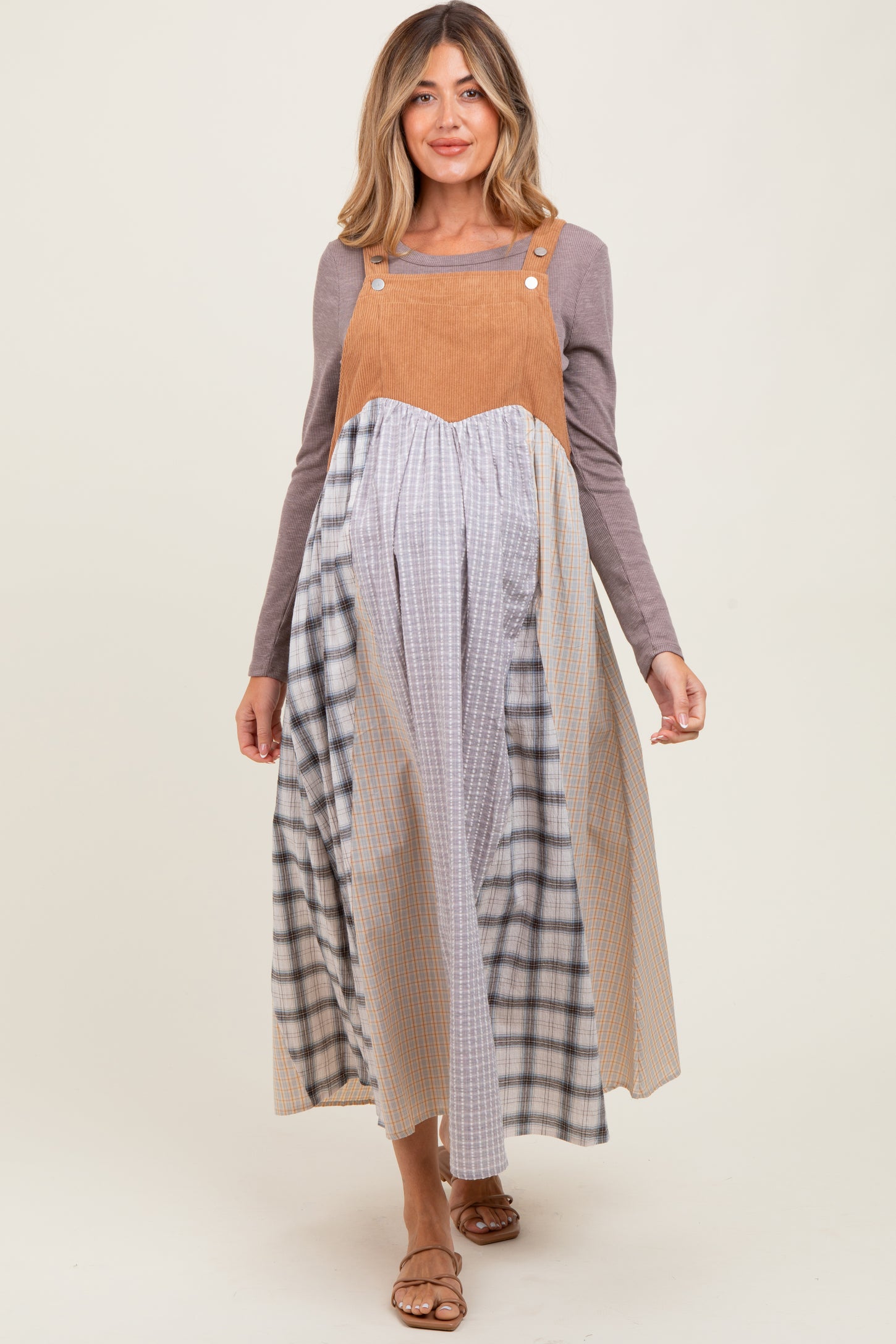 woman wearing a long maternity dress with a colorblock design in shades of tan, blue, and gray, with a fitted bodice and flowing skirt