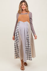 woman wearing a long maternity dress with a colorblock design in shades of tan, blue, and gray, with a fitted bodice and flowing skirt