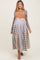 woman wearing a long maternity dress with a colorblock design in shades of tan, blue, and gray, with a fitted bodice and flowing skirt