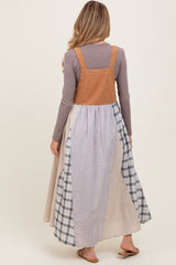 woman wearing a brown corduroy maternity dress with a long plaid skirt, viewed from the back